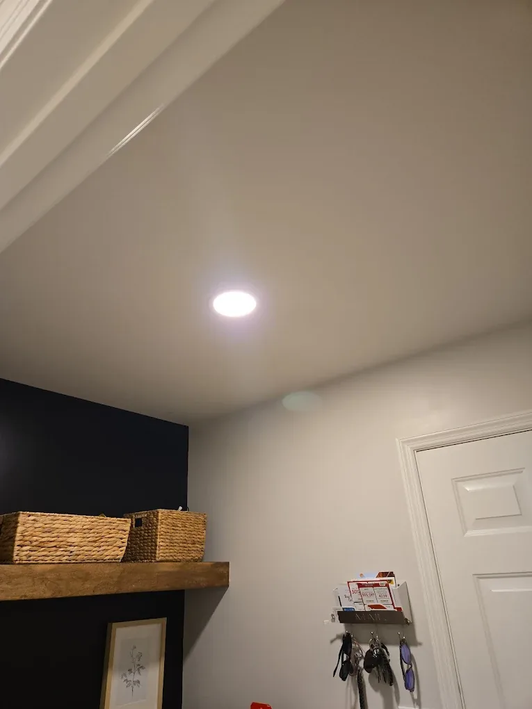 Recessed can light installed in a mudroom ceiling beside a navy accent wall